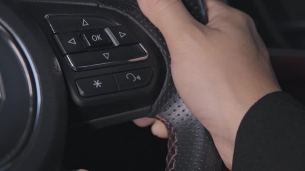 閉じるスーツを着た女性ドライバーの手を押すボタンを押すと 運転中にステアリングホイールの音声コマンド機能を有効または無効にすることができます 交通技術の概念 — ストック動画