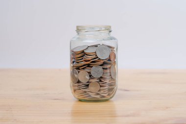 Glass jars with coins on wooden desk. Savings and Investments concept.
