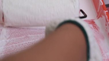 Koruyucu gözlük takan genç bayan dekoratör duvarları silindirle boyuyor. Onarım ve iç dekorasyon.