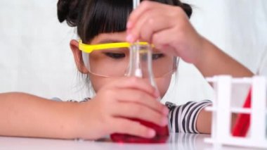 Çocuklar sınıfta öğreniyor ve fen deneyleri yapıyorlar. Evde eğitim için bilim deneyi yapan küçük bir kız. Evdeki çocuklar için kolay ve eğlenceli bilimsel deneyler..
