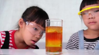 Çocuklar sınıfta öğreniyor ve fen deneyleri yapıyorlar. İki küçük kız kardeş evde eğitim için bilim deneyi yapıyor. Evdeki çocuklar için kolay ve eğlenceli bilimsel deneyler..