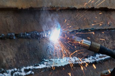 Kaynak makinesinin kapanışı. İşçi kaynak yapar kıvılcımlar saçan metal.