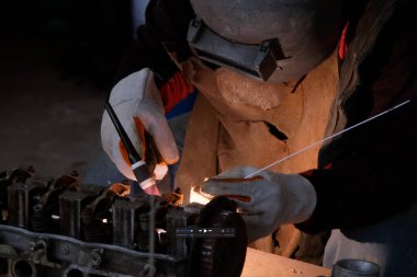 Kaynak maskesi ve eldiven giyen profesyonel adamlar kaynak ve argon ile ev atölyesinde çalışıyorlar..
