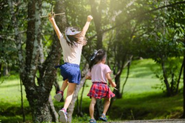 Mutlu çocuklar yaz bahçesinde karton uçaklarla oynuyorlar. Parkta yolda koşan oyuncak uçakları olan iki kız kardeş. Mutlu çocukluk kavramı.