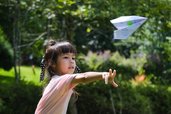 夏の庭で紙飛行機で遊ぶ幸せな子供たち 公園で紙飛行機を投げるかわいい女の子 幸せな子供時代のコンセプト — ストック写真