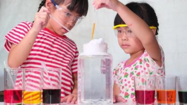 Çocuklar sınıfta öğreniyor ve fen deneyleri yapıyorlar. Evde eğitim için bilim deneyi yapan küçük bir kız. Evdeki çocuklar için kolay ve eğlenceli bilimsel deneyler..