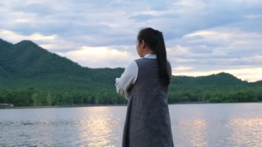 Şirin küçük kız gün batımında göl kenarında doğanın tadını çıkarırken annesine arkadan sarılarak koştu. Mutlu aile, anne ve kızı parkta mutlu bir şekilde oynuyorlar..