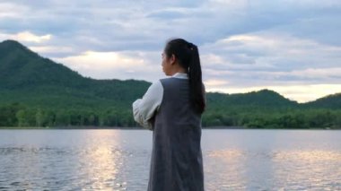 Şirin küçük kız gün batımında göl kenarında doğanın tadını çıkarırken annesine arkadan sarılarak koştu. Mutlu aile, anne ve kızı parkta mutlu bir şekilde oynuyorlar..