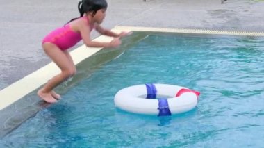 Lastik yüzüklü mutlu küçük kız kardeşler yaz tatili sırasında tropik bir tatil köyünde açık havuza atlıyorlar. Çocuklar yüzmeyi öğreniyor. Çocuklar için Sağlıklı Yaz Faaliyetleri.