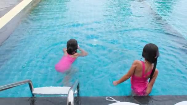 자매들은 휴가중에 휴양지인 수영장에서 수영을 아이들은 다이빙 수영을 배우죠 아이들을 — 비디오