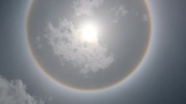 Aerial view of the sun with a circular rainbow surrounded by bright skies and white clouds. Phenomenon, sun halo. Natural background in motion. drone shooting sun and clouds motion time