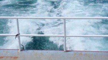 Bright sea water trail behind the ferry in the summer. Boat is leaving churning sea and waves behind. blue sea waves