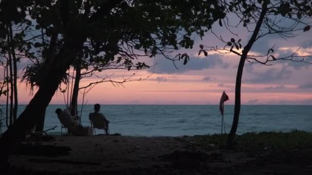 Ζευγάρια Κάθονται Και Βλέπουν Ηλιοβασίλεμα Δίπλα Στη Θάλασσα Σιλουέτες Γυναικών — Αρχείο Βίντεο