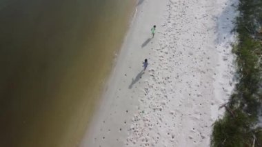 Aerial view from a drone of a happy Asian family of mother and daughters having fun playing on the beach during summer vacation. Summer family trip to the beach. travel and vacation concept.