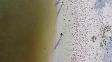 Aerial view from a drone of a happy Asian family of mother and daughters having fun playing on the beach during summer vacation. Summer family trip to the beach. travel and vacation concept.