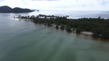 Beautiful aerial view of the sandy beach jutting out to the sea with lush tropical trees and soft blue ocean waves at Laem Haad Beach, famous tourist attraction of Koh Yao Yai, Phang Nga, Thailand.