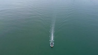 Aerial view from a drone of Thai traditional longtail fishing boats sailing in the sea. Top view of a fast moving fishing boat in the ocean.