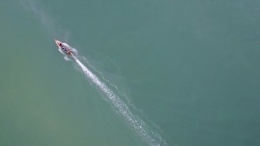 Aerial view from a drone of Thai traditional longtail fishing boats sailing in the sea. Top view of a fast moving fishing boat in the ocean.