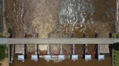 Aerial view of water released from the drainage channel of the concrete dam is a way of overflowing water in the rainy season. Top view of turbid brown forest water flows from a dam in rural northern Thailand.