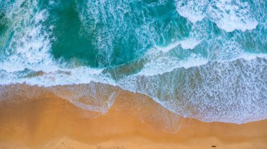 Beautiful sea waves and white sand beach in the tropical island. Soft waves of blue ocean on sandy beach background from top view from drones. Concept of relaxation and travel on vacation.