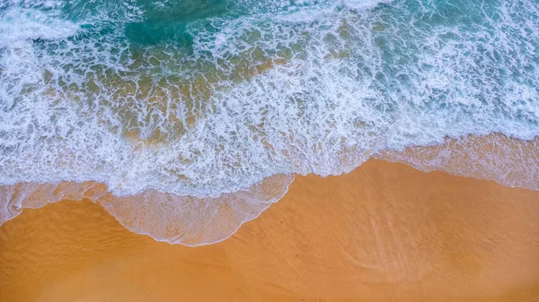 Beautiful sea waves and white sand beach in the tropical island. Soft waves of blue ocean on sandy beach background from top view from drones. Concept of relaxation and travel on vacation.