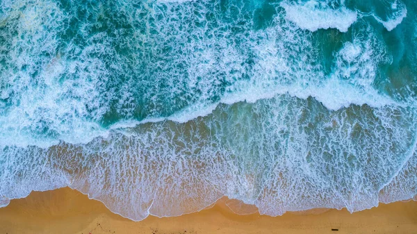 Beautiful sea waves and white sand beach in the tropical island. Soft waves of blue ocean on sandy beach background from top view from drones. Concept of relaxation and travel on vacation.