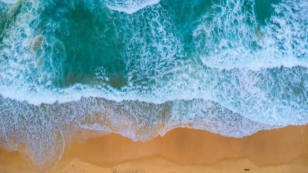 Beautiful sea waves and white sand beach in the tropical island. Soft waves of blue ocean on sandy beach background from top view from drones. Concept of relaxation and travel on vacation.