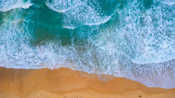 Beautiful sea waves and white sand beach in the tropical island. Soft waves of blue ocean on sandy beach background from top view from drones. Concept of relaxation and travel on vacation.