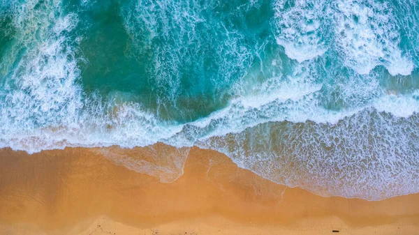 Beautiful sea waves and white sand beach in the tropical island. Soft waves of blue ocean on sandy beach background from top view from drones. Concept of relaxation and travel on vacation.