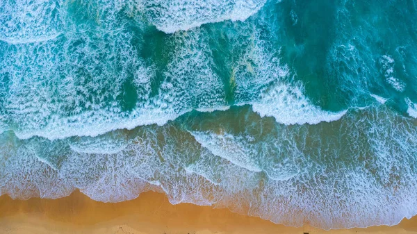 Beautiful sea waves and white sand beach in the tropical island. Soft waves of blue ocean on sandy beach background from top view from drones. Concept of relaxation and travel on vacation.