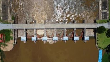 Aerial view of water released from the drainage channel of the concrete dam is a way of overflowing water in the rainy season. Top view of turbid brown forest water flows from a dam in rural northern Thailand.