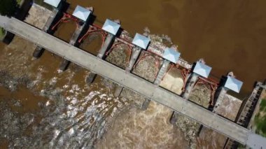 Aerial view of water released from the drainage channel of the concrete dam is a way of overflowing water in the rainy season. Top view of turbid brown forest water flows from a dam in rural northern Thailand.
