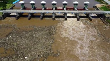 Aerial view of water released from the drainage channel of the concrete dam is a way of overflowing water in the rainy season. Top view of turbid brown forest water flows from a dam in rural northern Thailand.