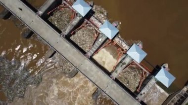 Aerial view of water released from the drainage channel of the concrete dam is a way of overflowing water in the rainy season. Top view of turbid brown forest water flows from a dam in rural northern Thailand.