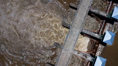 Yağmur mevsimindeki taşkınlık olarak beton barajın drenaj kanalından çıkan suyun hava görüntüsü. Kuzey Tayland 'daki bir barajdan turbiş kahverengi orman suyunun en üst görüntüsü akıyor.