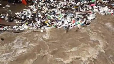 Yağmur mevsiminde kurak dallar ve Kuzey Tayland 'ın kırsal kesimindeki bir baraj kapısındaki plastik atıklarla su taşarken, beton baraj drenaj kanalları tarafından serbest bırakılan kubbeli kahverengi orman suyunun hava manzarası..