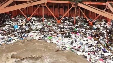 Yağmur mevsiminde kurak dallar ve Kuzey Tayland 'ın kırsal kesimindeki bir baraj kapısındaki plastik atıklarla su taşarken, beton baraj drenaj kanalları tarafından serbest bırakılan kubbeli kahverengi orman suyunun hava manzarası..