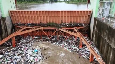 Yağmur mevsiminde kurak dallar ve Kuzey Tayland 'ın kırsal kesimindeki bir baraj kapısındaki plastik atıklarla su taşarken, beton baraj drenaj kanalları tarafından serbest bırakılan kubbeli kahverengi orman suyunun hava manzarası..