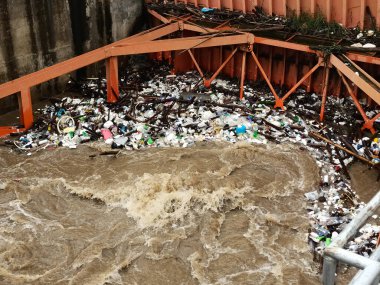 Yağmur mevsiminde kurak dallar ve Kuzey Tayland 'ın kırsal kesimindeki bir baraj kapısındaki plastik atıklarla su taşarken, beton baraj drenaj kanalları tarafından serbest bırakılan kubbeli kahverengi orman suyunun hava manzarası..