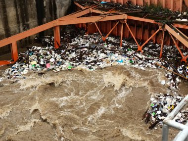 Yağmur mevsiminde kurak dallar ve Kuzey Tayland 'ın kırsal kesimindeki bir baraj kapısındaki plastik atıklarla su taşarken, beton baraj drenaj kanalları tarafından serbest bırakılan kubbeli kahverengi orman suyunun hava manzarası..