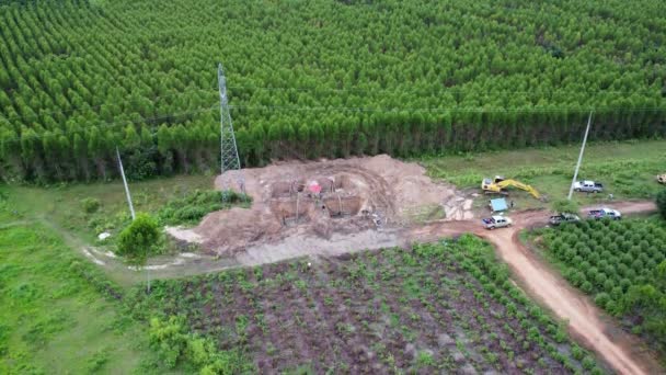 挖掘机的空中视图正在高压电塔的基座和高压电杆的腿上工作 森林中电力线建设的最高视图 — 图库视频影像