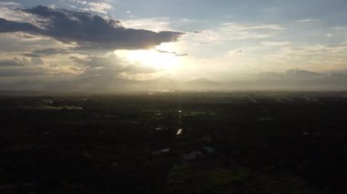 Güzel dağ siluetleri ve günbatımı gökyüzü olan kırsal köy manzarasının insansız hava aracı görüntüleri.