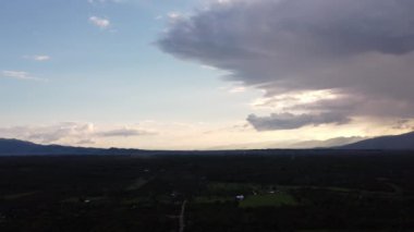 Gün batımında bulutlu ve güneşli güzel gökyüzü manzarası. Gökyüzündeki bulutların zaman geçişi, güneşin altın ışınlarıyla dağ siluetinin arka planına karşı.