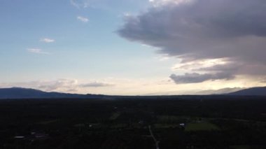 Gün batımında bulutlu ve güneşli güzel gökyüzünün, dağ manzaralarının siluetlerinin ve kırsal köylerin arkaplanlarına çarpması. doğa gökyüzü arkaplanı