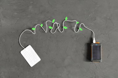Taşınabilir ısıtıcı, gri dokusal arka planda güneş paneli olan USB ile bağlantı güç bankasına bağlı. Yeşil enerji ve çevre koruma kavramı