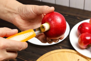 Elinde koca kırmızı bir elma, özel bıçaklı bir adam elmanın çekirdeğini kesiyor, seçici bir odak noktasıyla yakın plan.