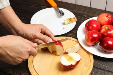 Eller kesme tahtasında bıçakla sulu kırmızı elma, tatlı olarak çekirdeksiz elma pişirme, yakın plan.