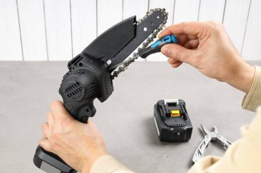 Yakın plan, tornavidayla el portatif testereye bağlanmamış pille zincir çeker. Seriden, iş için araç hazırlığı