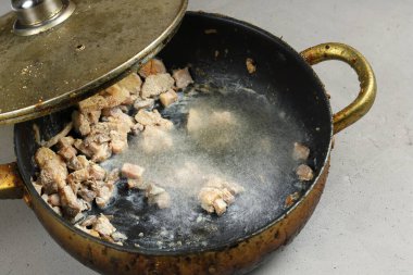 Stored for long time old frying pan with spoilt products inside, covered with mold and unsuitable for eating because of harmful mold