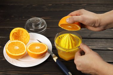 Hand keep half orange to squeeze fresh juice with juicer